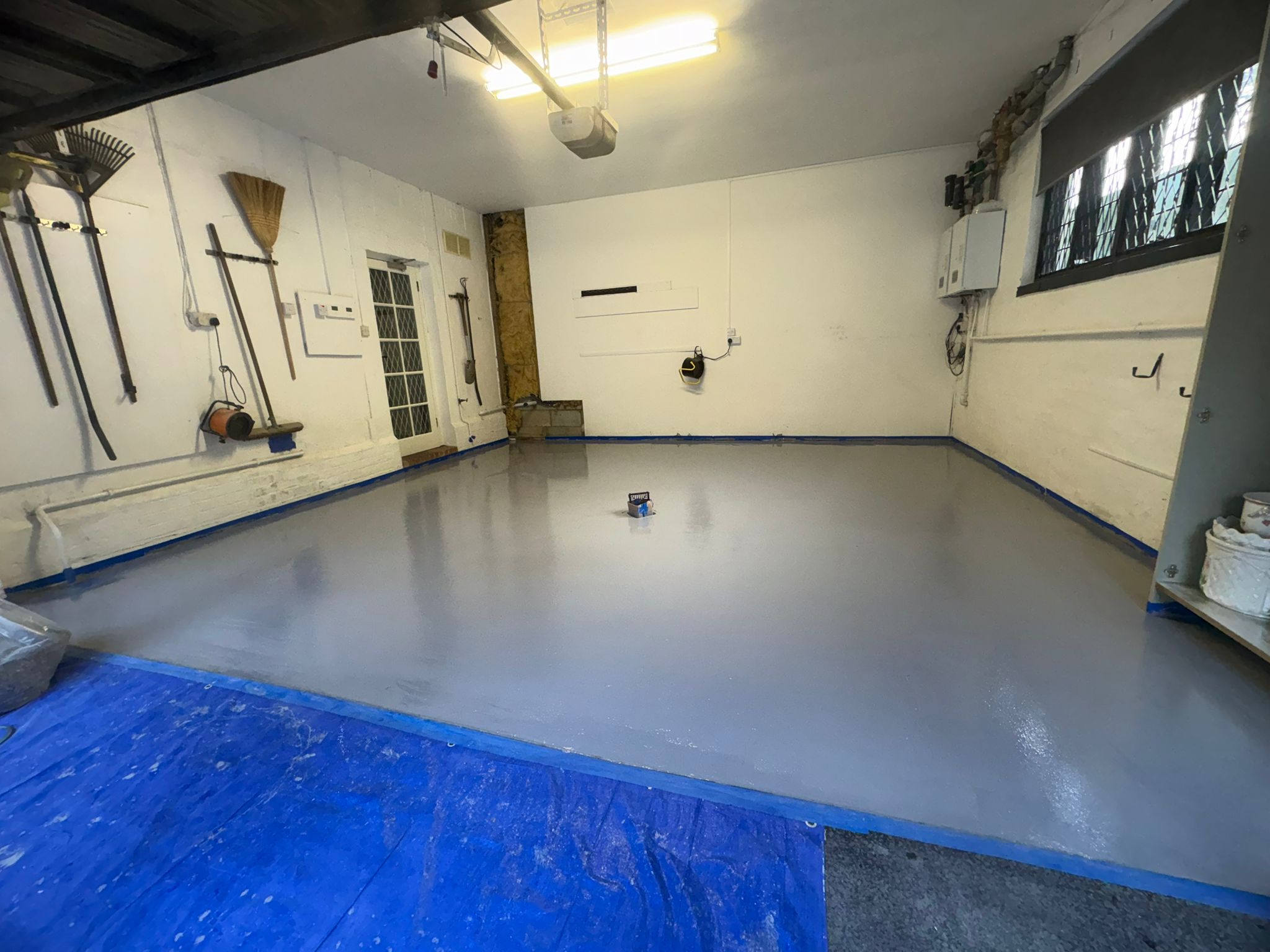 Wide grey garage floor with preparation materials still visible